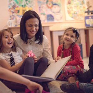 Happy preschool teacher telling stories to group of kids.