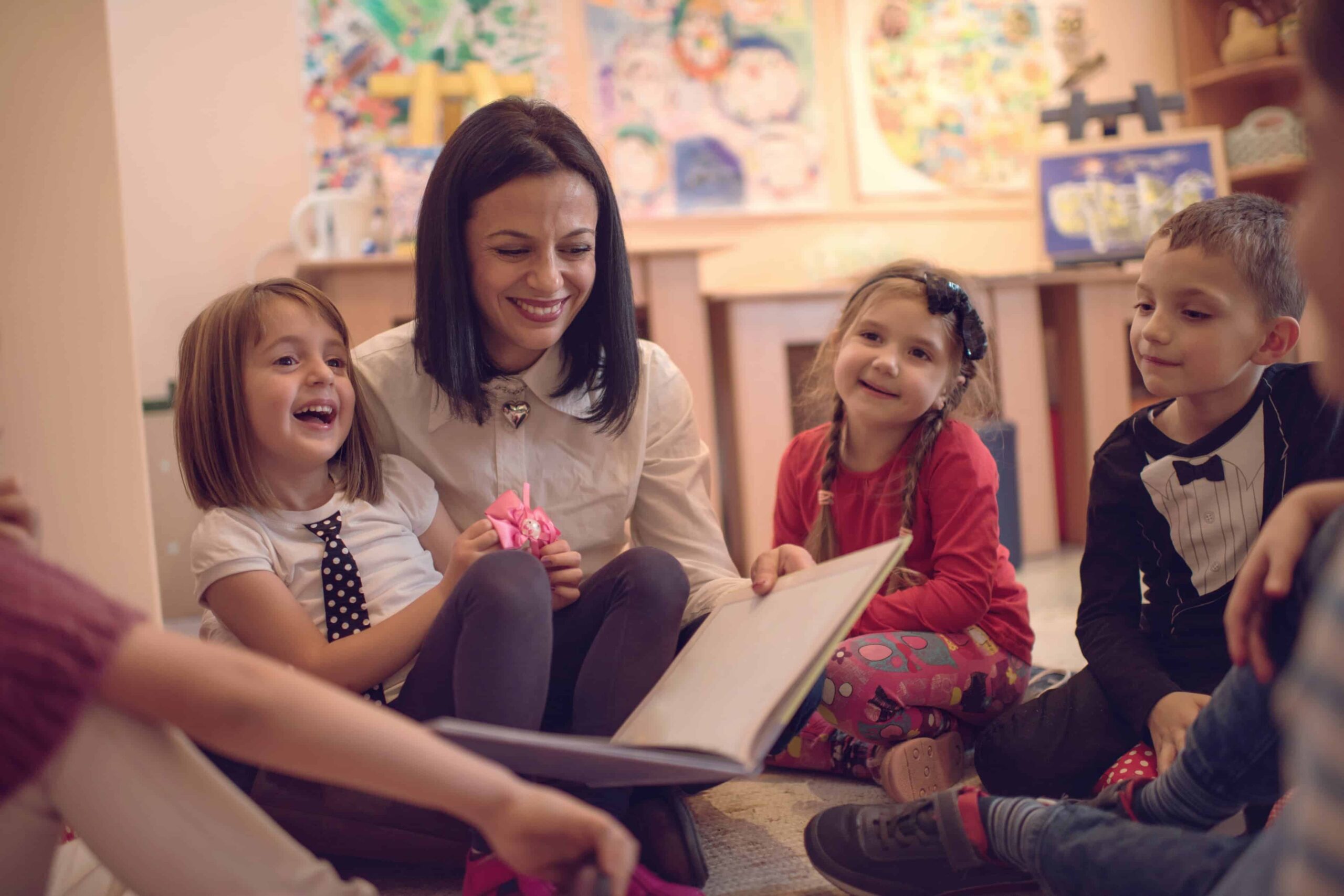 Happy preschool teacher telling stories to group of kids.