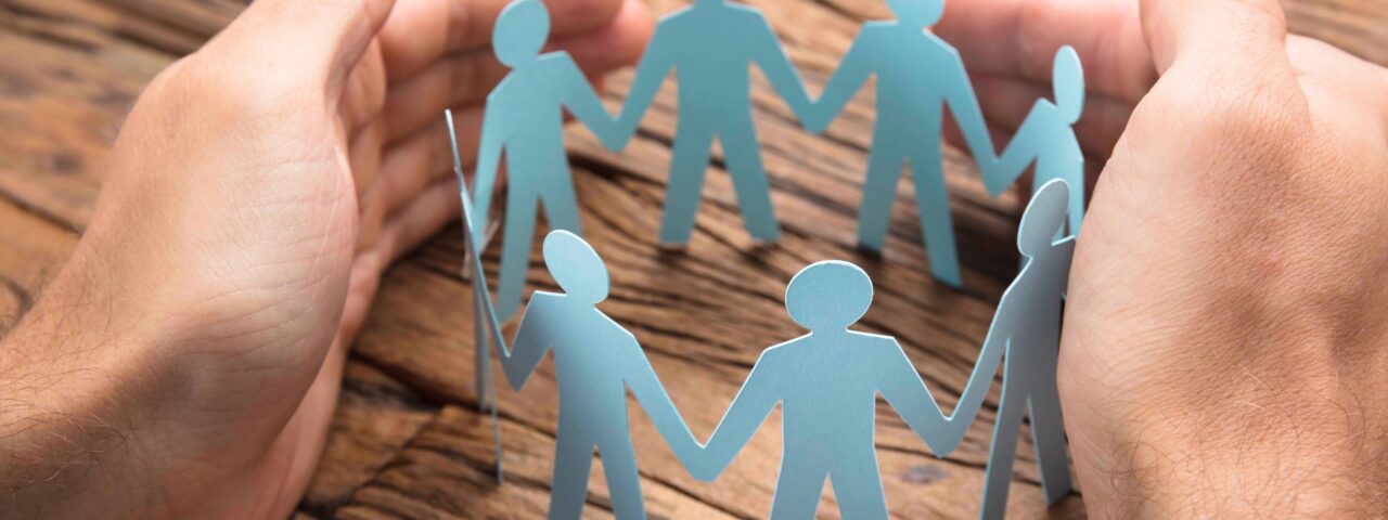 Businessman's Hands Covering Paper Team On Table