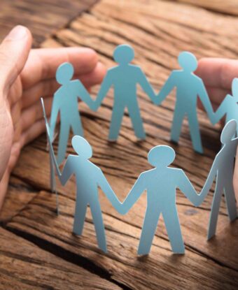 Businessman's Hands Covering Paper Team On Table