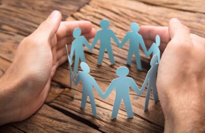 Businessman's Hands Covering Paper Team On Table