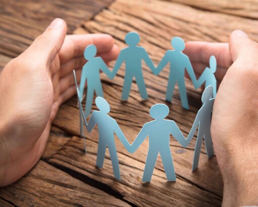 Businessman's Hands Covering Paper Team On Table