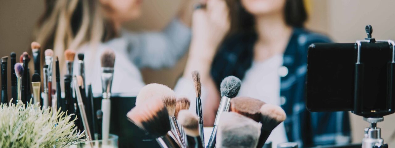 A close up on some makeup brushes with students in the background