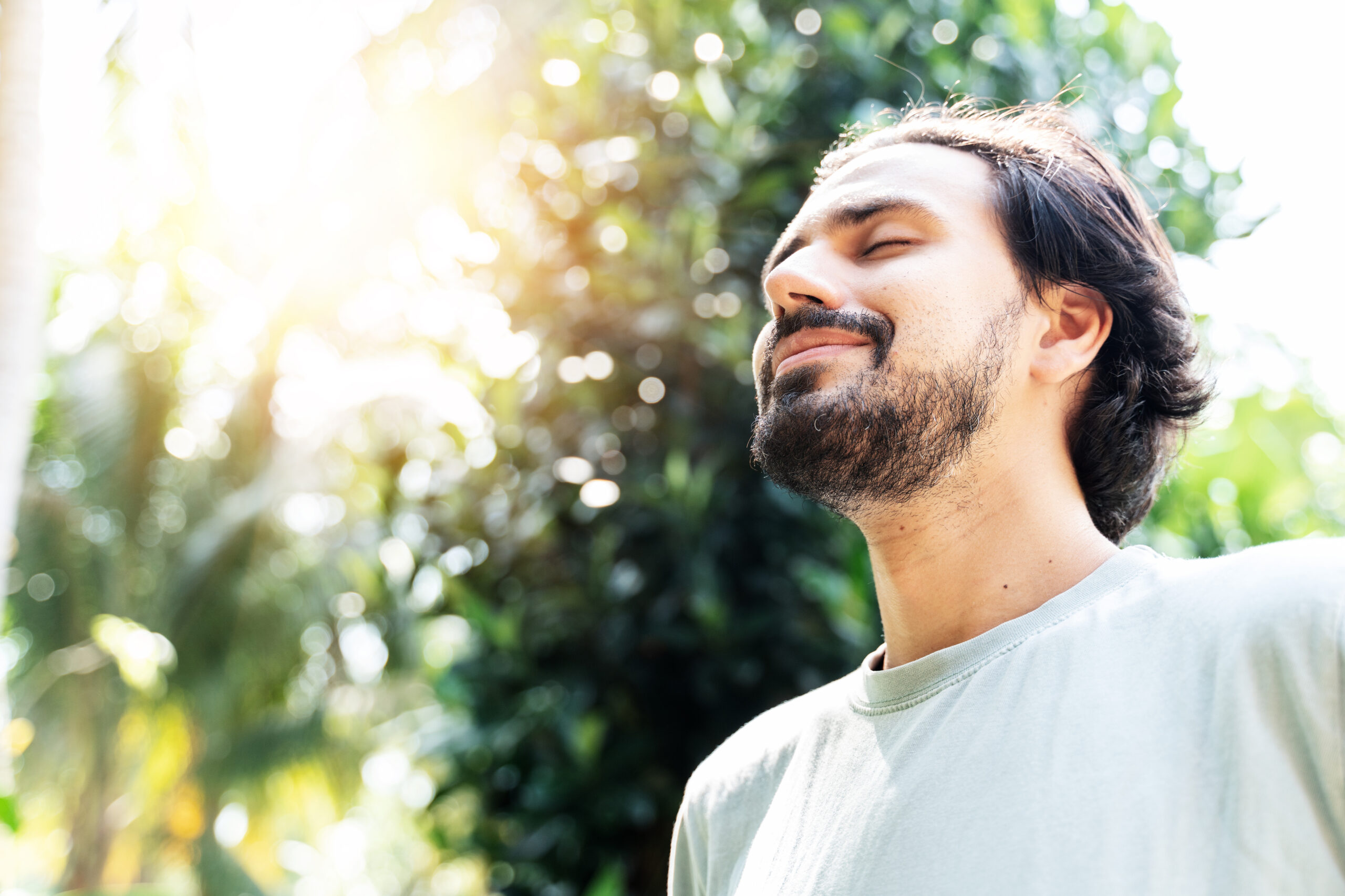 A Bearded Man Is Meditating Outdoor In The Park With Face Raised Up To Sky And Eyes Closed On Sunny Summer Day. Concept Of Meditation, Dreaming, Wellbeing Healthy Lifestyle A man breathing in fresh air outdoors