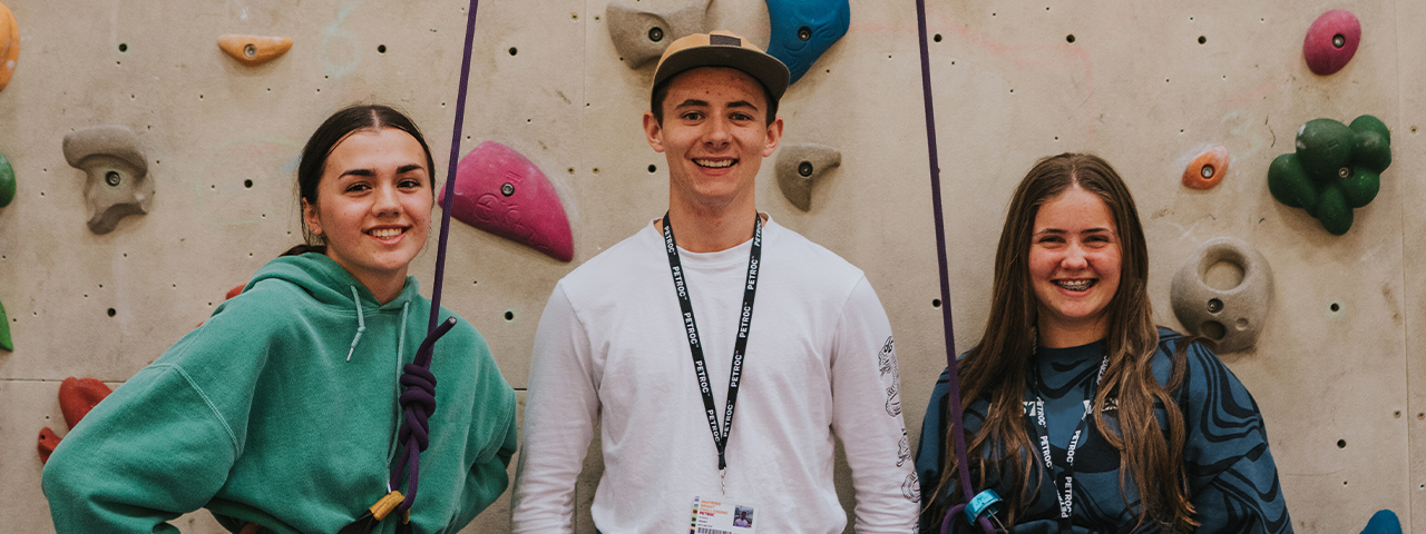 Enrichment students standing in front of a climbing wall.