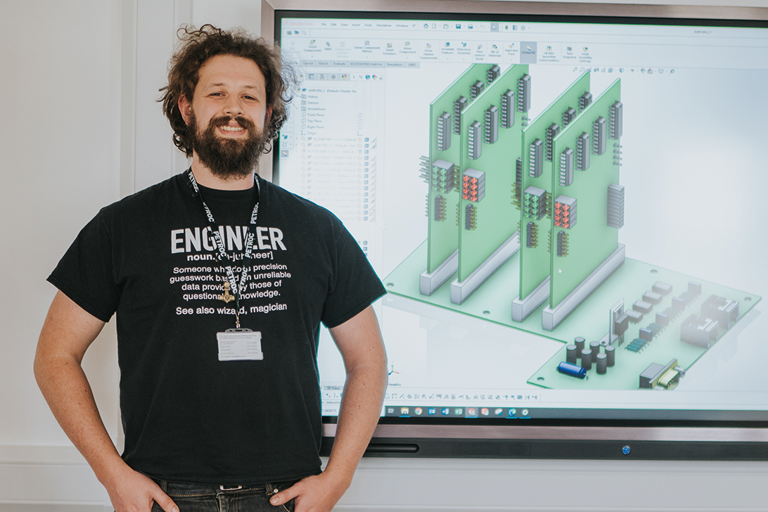 Man standing in front of a screen showing engineering images