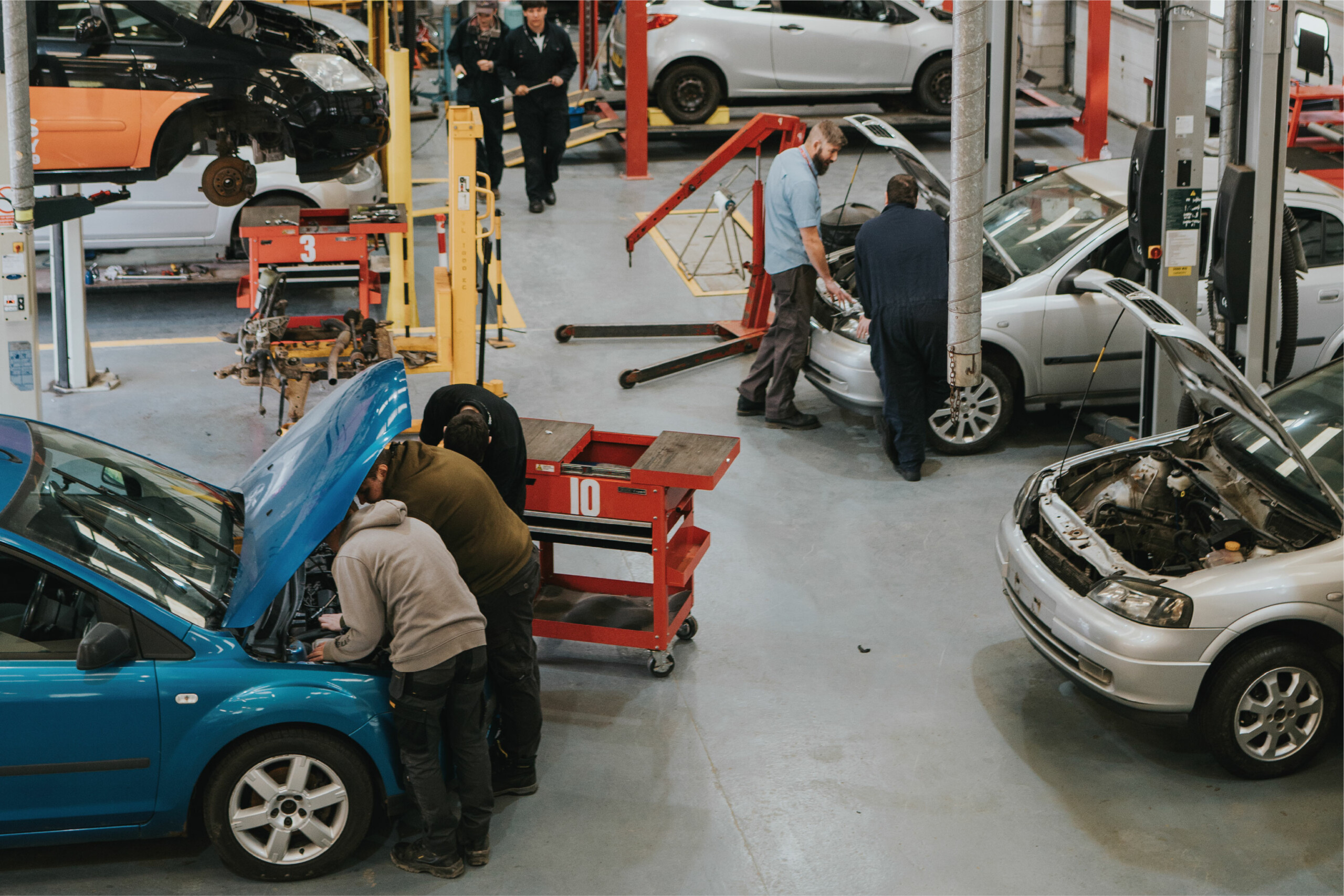 apprentice students looking under bonnet of car